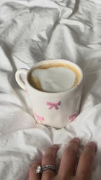 Pink bow mug with latte, picked up in hand