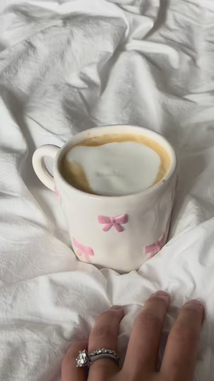 Pink bow mug with latte, picked up in hand