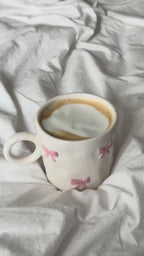 Pink bow mug with latte on white bedding