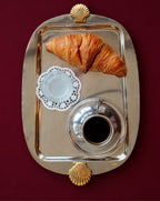 Silver serving tray with croissant and coffee on burgundy